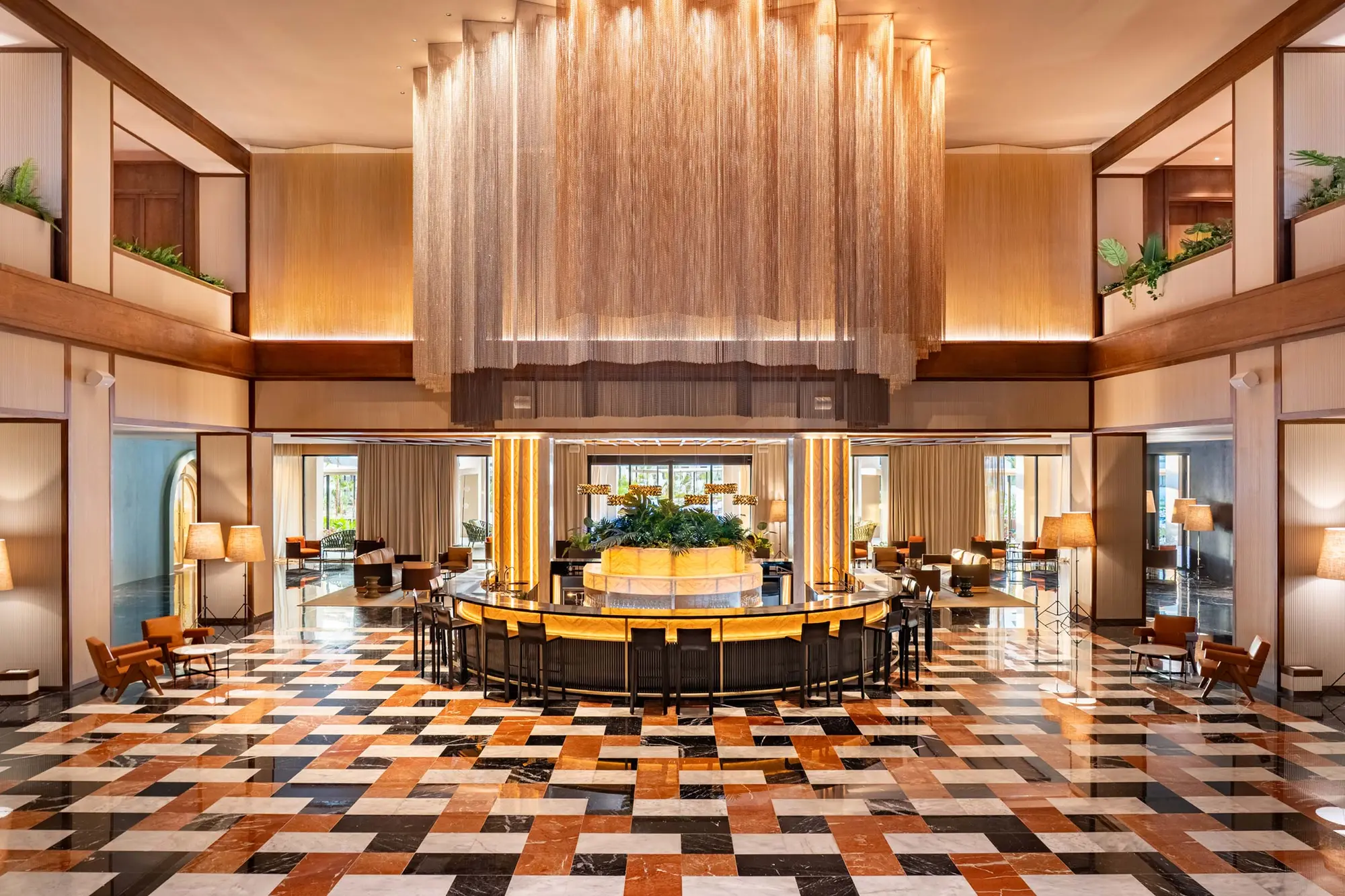 Lobby de hotel terminado con bar central y suelo de mármol en damero
