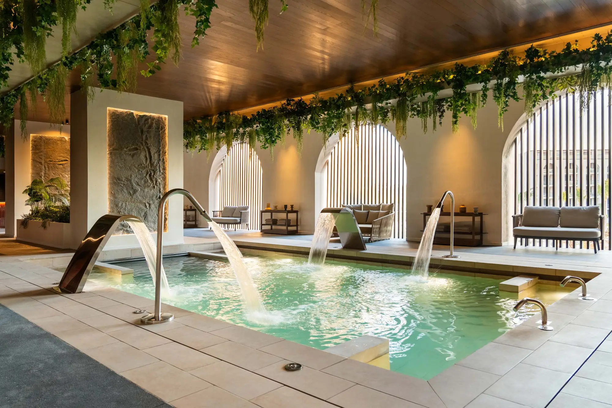 Zona de spa con alberca interior, arcos y vegetación colgante